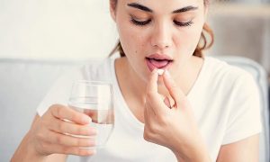 Mujer tomando pastilla para el dolor de garganta